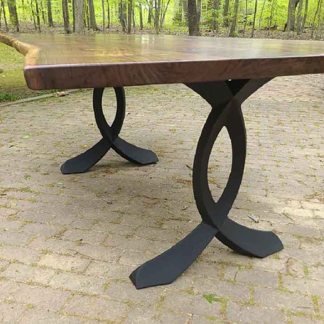 Patio wooden table with curved design metal table legs under natural sunlight.