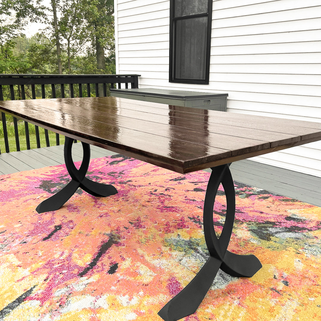 Patio natural wooden table with 423 Curva 28" H curved design metal table legs under natural sunlight.