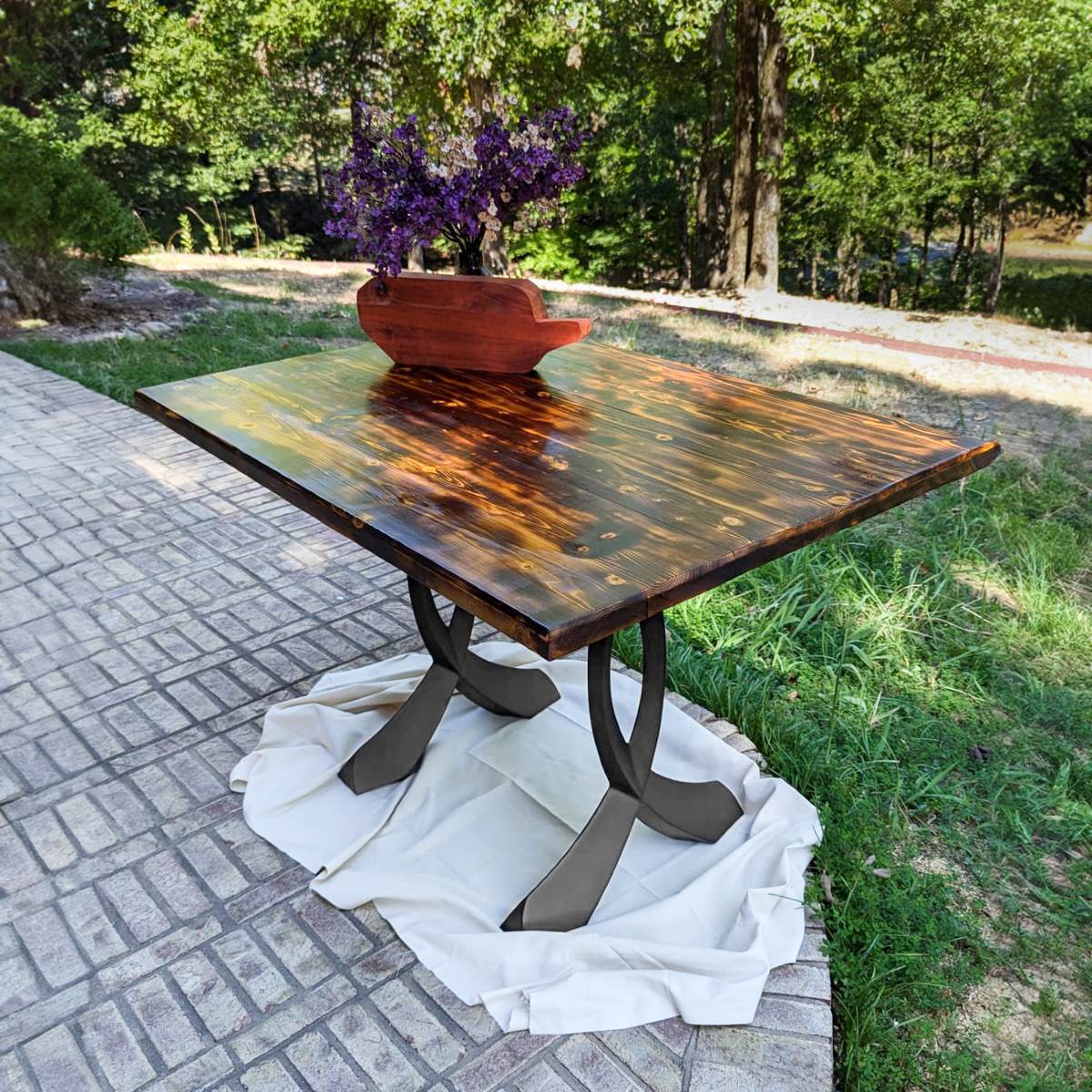 Outdoor epoxy dining table supported by sculptural curved design metal table legs.