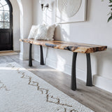 wooden bench with black legs in a room with a rug and wall art