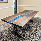 Epoxy river table on curved design metal table legs in indoor setting.