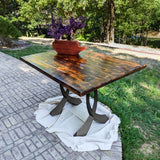 Outdoor epoxy dining table supported by sculptural curved design metal table legs.